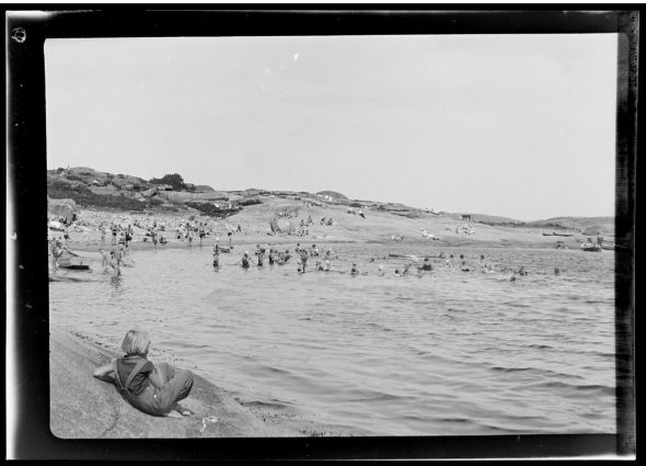 Badende mennesker, strand og svaberg i Norge med gutt i forkant på 1920-tallet. Sommer i gamle dager.
