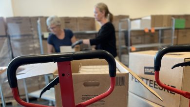 To kvinner jobber med store mengder arkiv i pappesker.