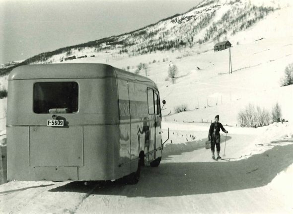 Bokbussen på snødekt vei i Ål, låntager på ski ved bussen
